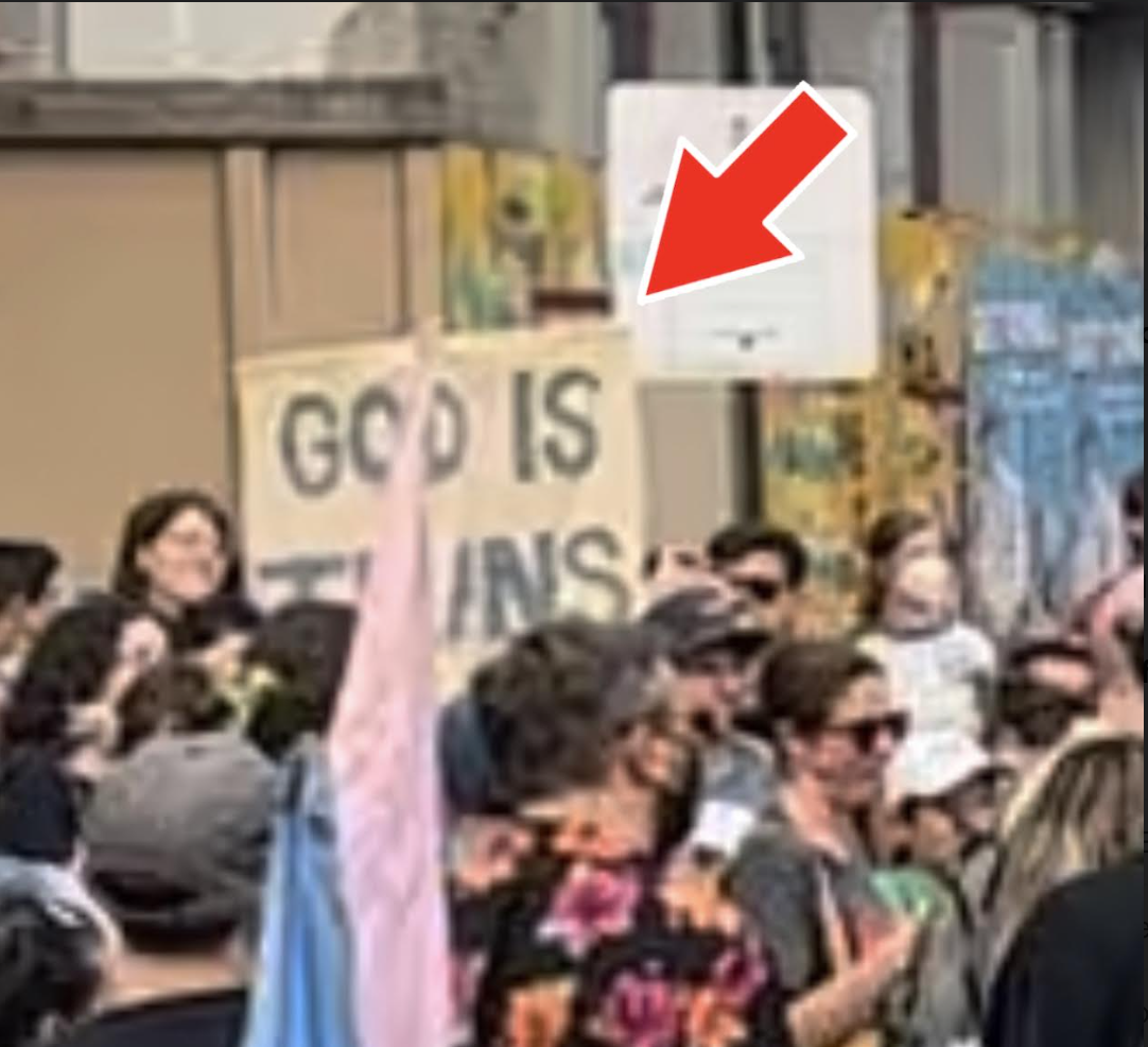 'God is Trans' sign at Philadelphia protest against Moms for Liberty